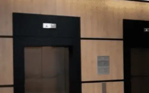 Elevator doors and call sign in an elevator lobby finished in ZX149 Nordic Pine wood film
